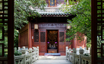 Ivy-clad courtyard with traditional red wooden doors at Amanfayun, framed by dark timber archway.