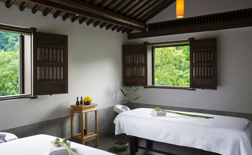 Two beds in a serene bedroom at Amanfayun, with wooden windows framing garden views.