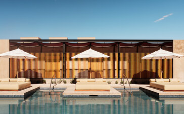Amangiri wellness pavilion with floor-to-ceiling windows overlooking a plunge pool and desert landscape at dusk.