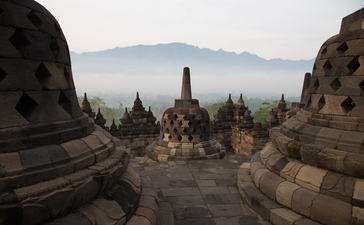 Stone temple ruins framing a distant volcanic peak at Amanjiwo.