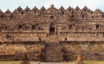 Borobudur temple complex at Amanjiwo, Indonesia, with intricate stone architecture and multiple Buddha stupas visible across the tiered structure.