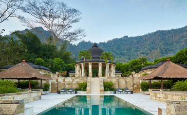 Amanjiwo's central courtyard with reflecting pool and traditional stone pavilion, surrounded by mountains and lush gardens.