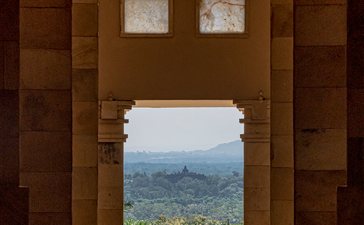 View through wooden temple doorway to terraced valleys at Amanjiwo