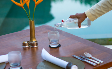 Dining table at Amanjiwo resort with bird of paradise flower arrangement and water views beyond.