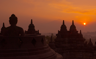 Silhouetted Buddhist temples at sunset, Amanjiwo resort, Java.
