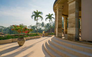Terrasse couverte avec colonnade donnant sur jardins et volcans lointains à Amanjiwo.