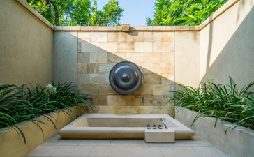 Amanjiwo wellness sanctuary with circular water feature and stone platform, framed by verdant planting.
