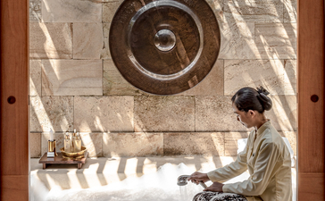 Guest practising yoga beneath a ceiling fan at Amanjiwo wellness space.