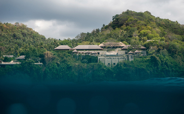 Amankila resort nestled on a hillside above clear turquoise waters, Bali.