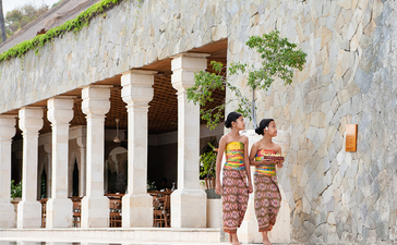 Deux femmes se tiennent près d'une piscine à débordement à Amankila, un resort balinais avec architecture coloniale.