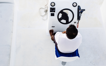 Aerial view of a person floating on a blue and white raft in clear turquoise water at Amanpulo resort.