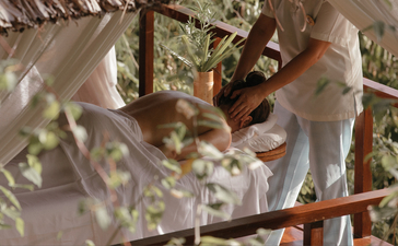 Wellness therapist administering a treatment at Amanpulo resort, surrounded by natural foliage.