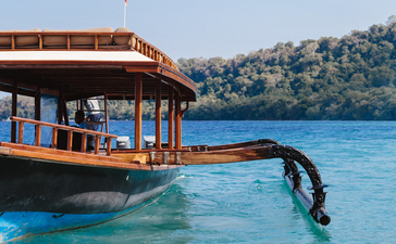 潜水员从安缦湾澜度假村的传统木船跳入清澈蔚蓝的海水中。