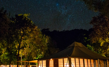 安缦湾澜度假村的帐篷客房在夜幕下闪烁灯光，星空璀璨。