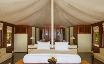 安缦湾澜度假村宽敞的主卧室，配有四柱床和米色纱幔。