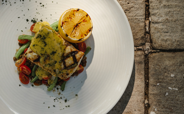 安缦湾澜度假村餐饮，白盘盛装烤玉米片、绿色蔬菜和彩色配菜。