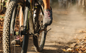 安缦湾澜度假村内，骑行者骑着山地自行车穿过尘土飞扬的小径。