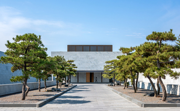 Contemporary gallery building at Amanyangyun framed by mature trees and open courtyard.