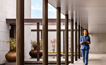 Visitor walking beneath wooden column structure at Amanyangyun gallery entrance.