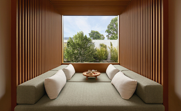 Two curved white chairs facing expansive windows overlooking gardens at Amanyangyun wellness retreat.