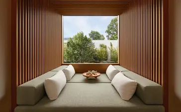 Two curved white chairs facing expansive windows overlooking gardens at Amanyangyun wellness retreat.