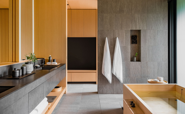 Aman Kyoto bathroom with concrete surfaces, wooden accents, and a deep soaking tub.
