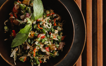 Overhead view of a noodle dish with vegetables and herbs in a black bowl at Amandari.