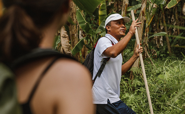 Staff member guiding a visitor through lush gardens at Amandari.