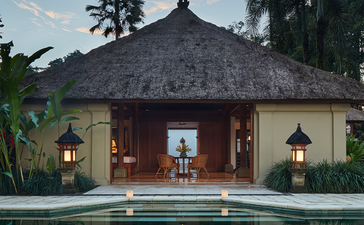 Amandari suite with thatched roof pavilion reflected in still pool at dusk, Bali.