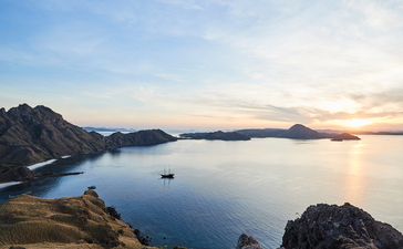 Sunset over calm waters at Amandira, with rocky headlands framing the bay.