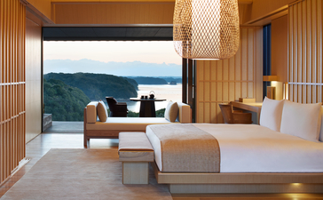 Nagi Suite bedroom at Amanemu with panoramic bay views, featuring natural wood finishes and contemporary furnishings.