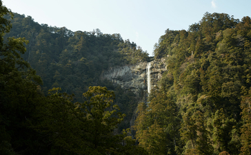 Waterfall cascading down a forested hillside at Amanemu resort.