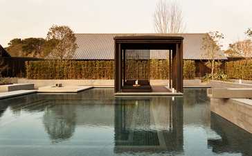 Serene plunge pool reflecting modern pavilion at Amanemu resort at dusk.