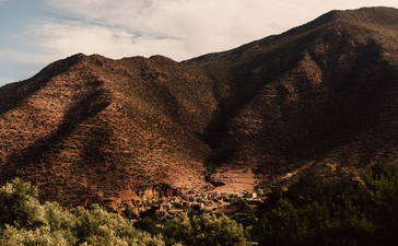 Arid mountain landscape at Amanjena with terracotta-hued slopes and sparse vegetation.