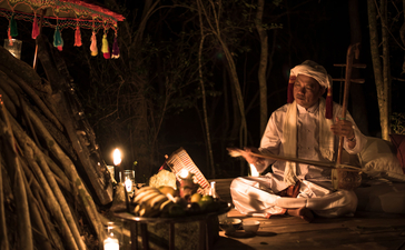 Amanoi guest preparing a meal by candlelight amongst palm trees at dusk.