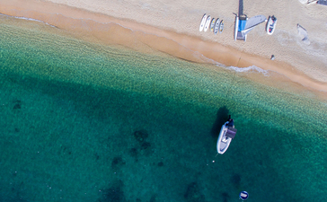 Aerial view of Amanoi's sandy beach with turquoise waters and moored boats.