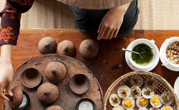 Overhead view of a traditional Vietnamese conical hat beside a wooden tray of quail eggs and bowls of ingredients at Amanoi.