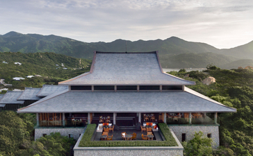 Amanoi's architectural pavilion with sweeping roof overlooks forested valley and distant mountains.