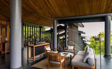 Amanoi villa terrace with wooden furniture, green shutters and coastal views.