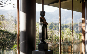Sunlit pavilion at Amanoi with floor-to-ceiling windows framing verdant landscape views.