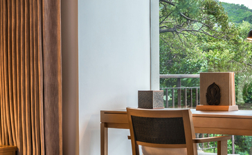 Wooden desk and chair beside large window with mountain views at Amanoi.