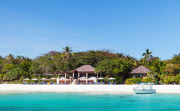 安缦璞乐度假村海滨景观，白沙滩与翠绿植被相映，清澈蓝绿色海水在前。