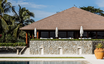 安缦璞乐度假村的游泳池，背景为棕榈树和茅草顶凉亭。