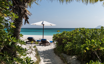安缦璞乐度假村海滩景观，白沙小径通向碧蓝海水与遮阳伞。