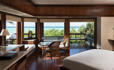 安缦璞乐度假村的宽敞卧室，配有大床、木质家具和落地窗，可眺望热带景观。