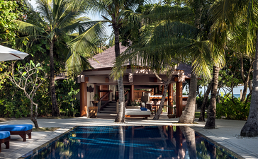 安缦璞乐度假村游泳池，周围棕榈树环绕，建筑倒映水面。