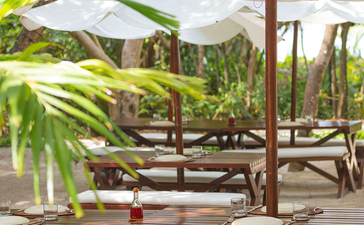 安缦璞乐度假村户外休闲区，配有遮阳伞和木制躺椅，周围绿植环绕。