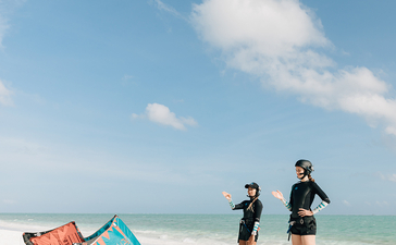 两位访客在白沙滩边观看彩色风筝，安缦璞乐度假村。