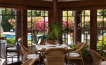 安缦璞乐度假村宽敞起居室，落地窗外绿景环绕，室内摆放木制家具和绿植。