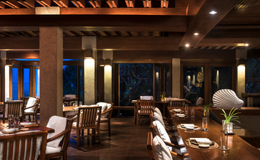 安缦璞乐度假村宽敞的餐厅内部，木质天花板和柔和的灯光营造温暖氛围。